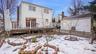 Snow covered house with fence, a wooden deck, and a chimney