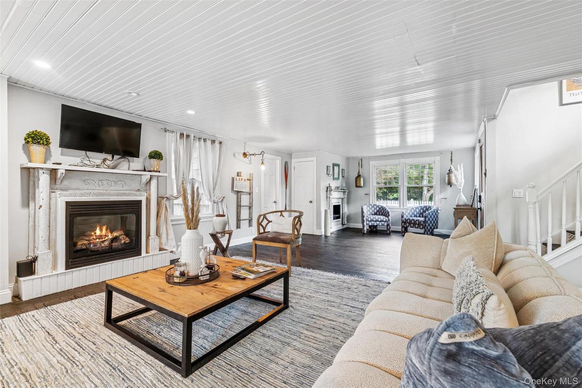 Living area with a glass covered fireplace, wood finished floors, and stairway