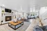 Living area with a glass covered fireplace, wood finished floors, and stairway