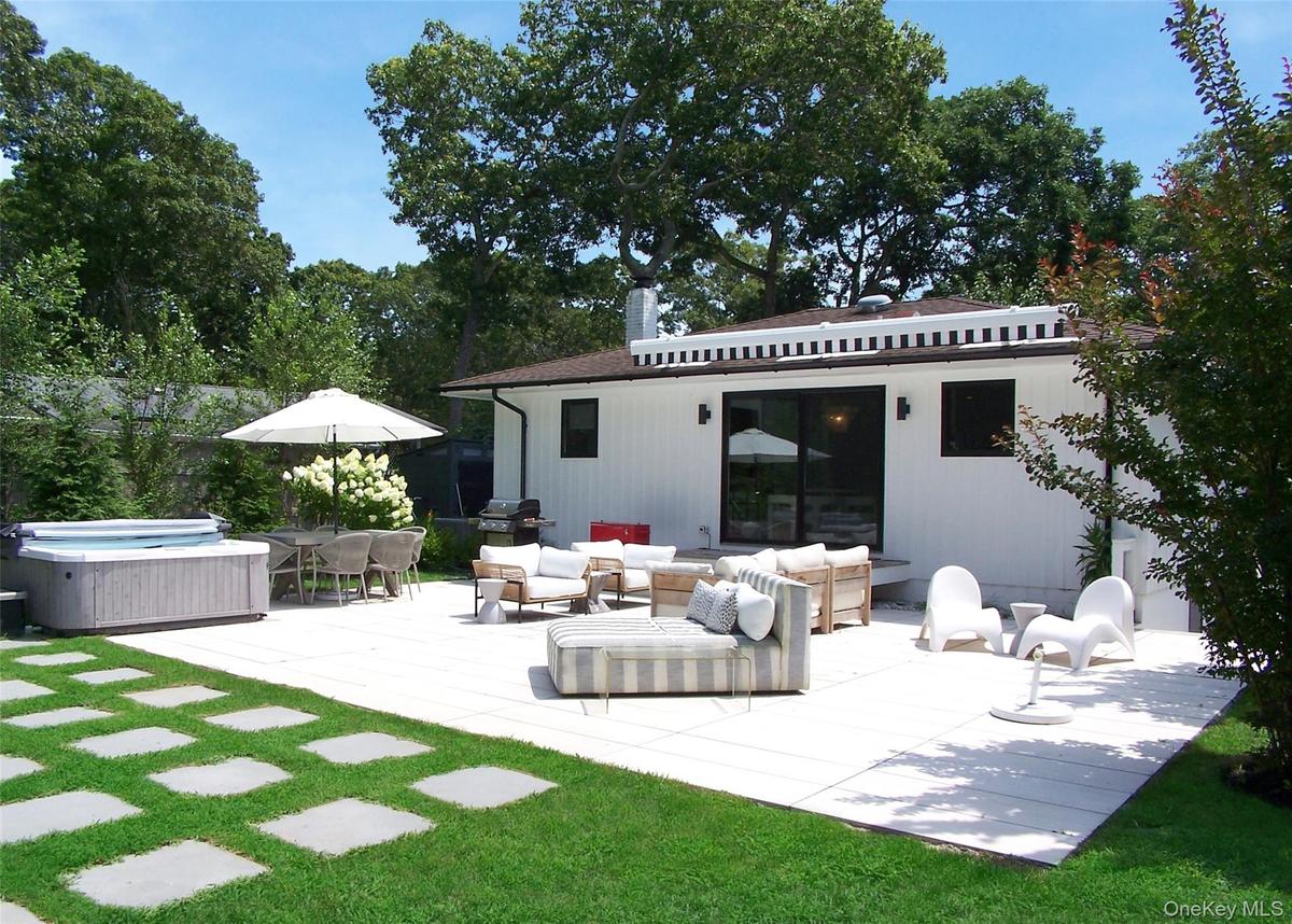 Rear view of house with an outdoor living space, a hot tub, outdoor dining space, a patio, and view of scattered trees