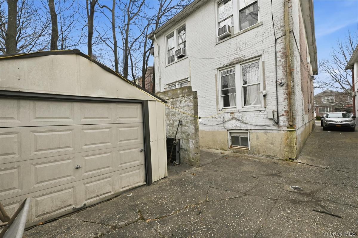 View of side of home featuring brick siding, a garage, and an outdoor structure