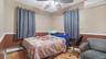 Bedroom featuring a baseboard heating unit, a ceiling fan, wood finished floors, and a wall mounted AC