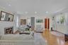 Spacious living area featuring parquet wood-finish flooring, recessed lighting, a white brick fireplace, and ample natural light from multiple windows