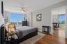 Bedroom 2 featuring a large window with city and tree-lined panoramas, wood-finish flooring, light gray wall paint, and a ceiling fan
