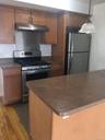 Kitchen featuring stainless steel appliances, under cabinet range hood, dark countertops, and pendant lighting