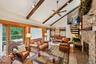Living room featuring beam ceiling, high vaulted ceiling, a ceiling fan, stairway, and a fireplace