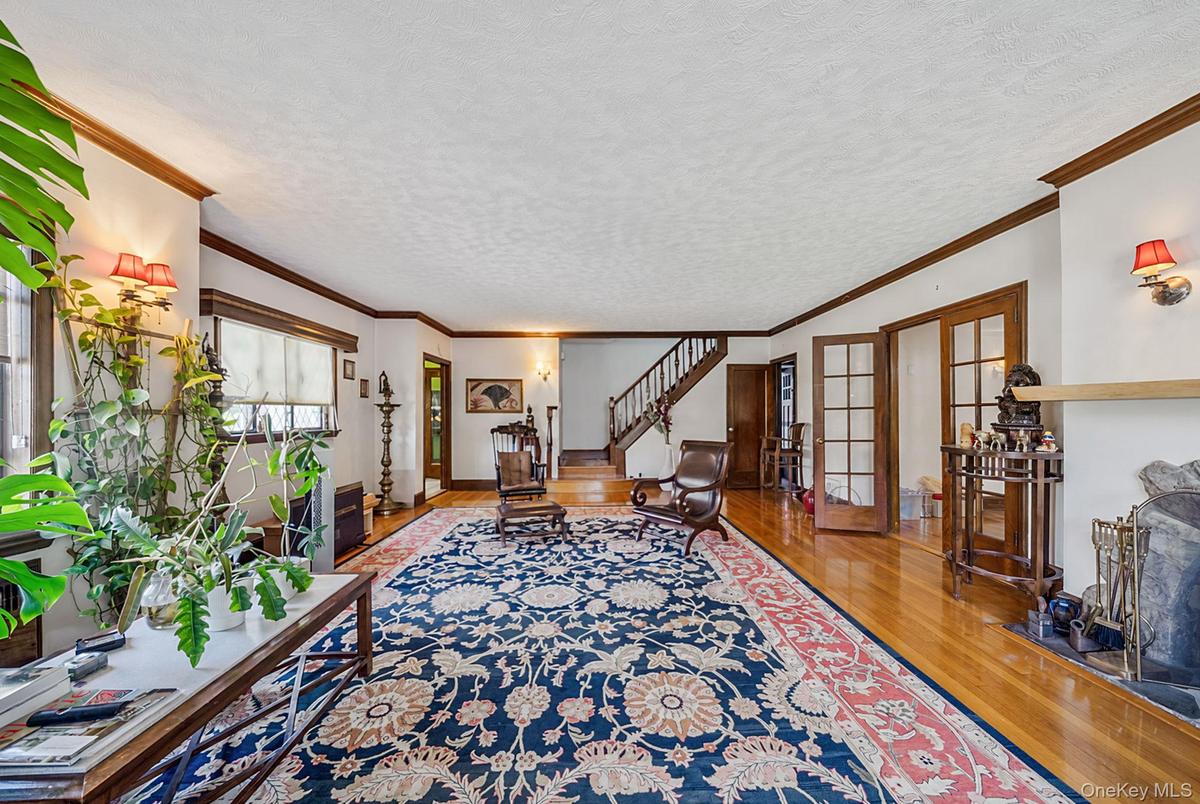 Spacious interior featuring hardwood flooring, detailed crown molding, a built-in fireplace, and double French doors with transom windows