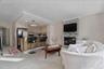 Living area with a stacked stone fireplace, recessed lighting, and crown molding