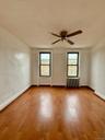 Empty room featuring plenty of natural light, radiator heating unit, wood finished floors, and ceiling fan