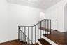 Stairs with arched walkways, wood finished floors, and baseboards