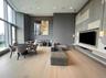 Living room with light wood-type flooring, an accent wall, and a towering ceiling