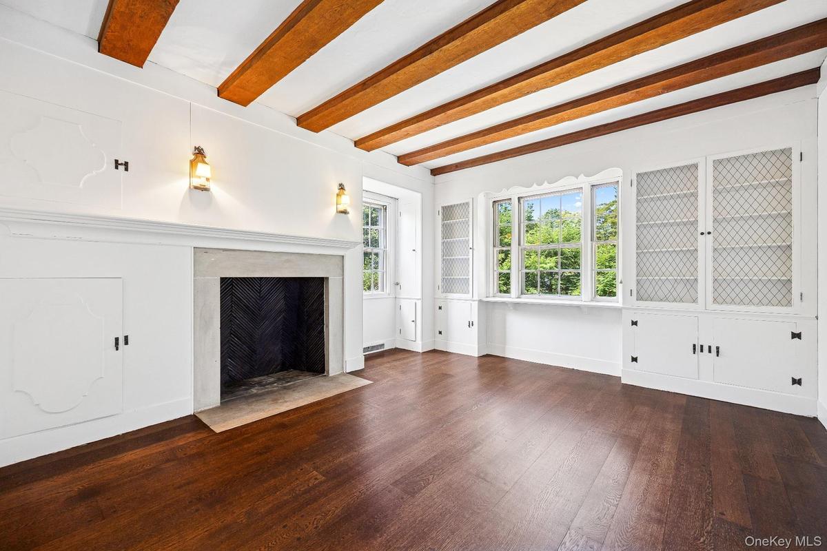 Unfurnished living room with beamed ceiling, a high end fireplace, and wood finished floors