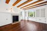 Unfurnished living room with beamed ceiling, a high end fireplace, and wood finished floors