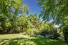 Expansive lawn area surrounded by mature trees and varied foliage