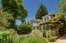 Shingle-sided residence with white picket fence and mature landscaping