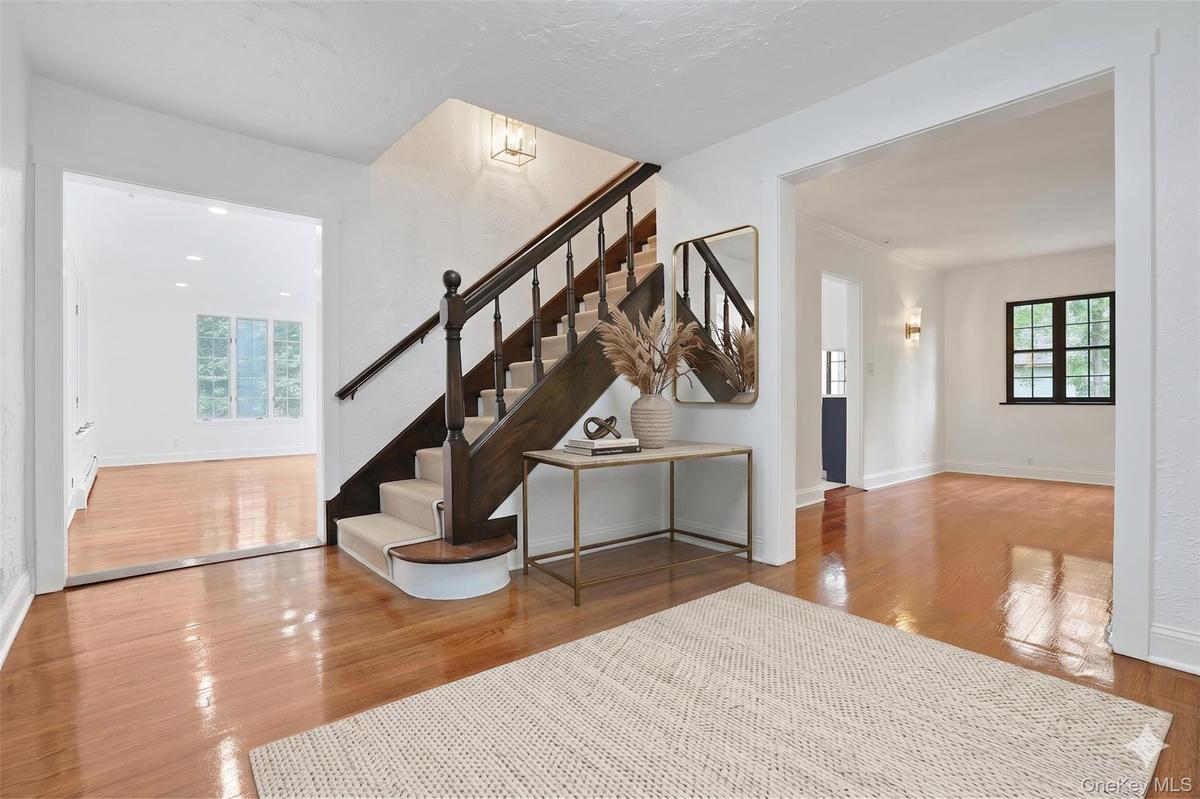 An inviting entry sets the tone for the home, where beautifully refinished hardwood floors, crisp white walls, and the original staircase showcase the