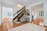 An inviting entry sets the tone for the home, where beautifully refinished hardwood floors, crisp white walls, and the original staircase showcase the