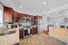 Kitchen featuring stainless steel appliances, light stone counters, recessed lighting, decorative backsplash, and dark wood finish cabinets