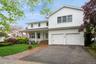 Traditional-style home with driveway, a front yard, an attached garage, and covered porch