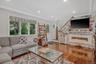 Living room with crown molding, wood finished floors, recessed lighting, and a stone fireplace