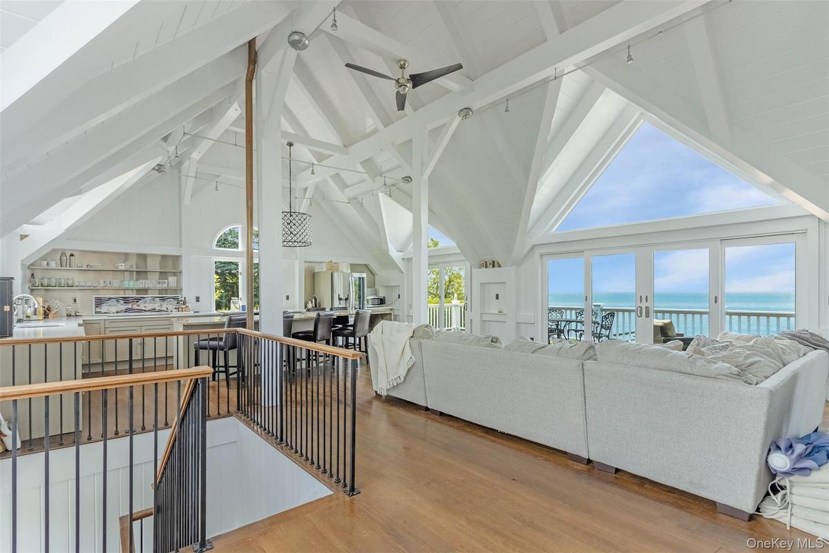 Living area with ceiling fan, a water view, beamed ceiling, plenty of natural light, and high vaulted ceiling