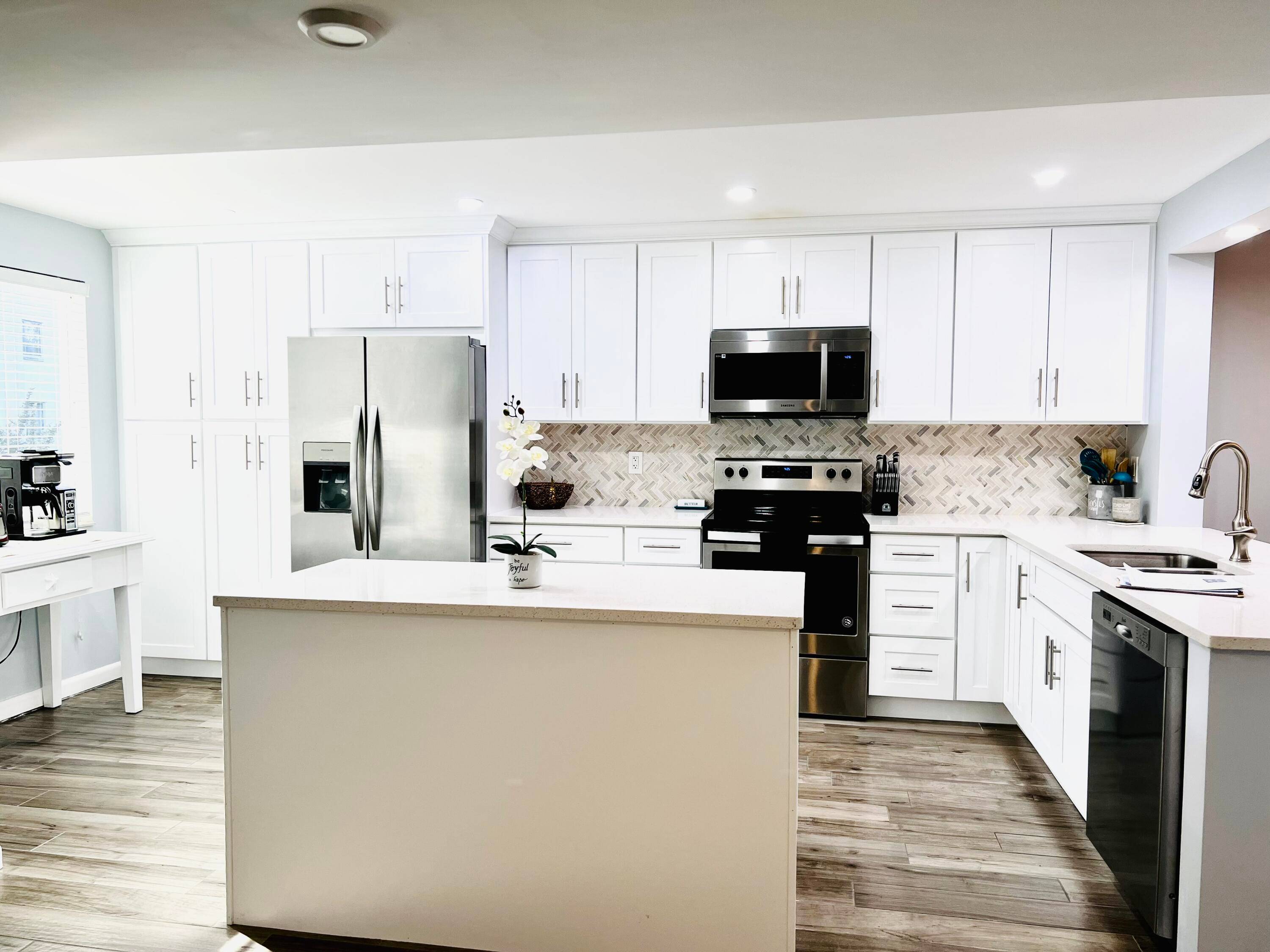 Renovated Condo with open kitchen, stainless steel appliances, white shaker style wood cabinets, quartz counters, and a large center island.