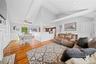 Living room featuring a decorative wall, wainscoting, vaulted ceiling, light wood-style flooring, and baseboard heating