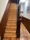 Stairway with wood-type flooring, crown molding, wainscoting, and wood walls