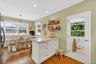 Kitchen with light stone countertops, a peninsula, white cabinetry, pendant lighting, and open shelves