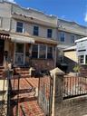 View of front of house with a fenced front yard, a gate, stone siding, cooling unit, and covered porch