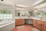 Spacious primary bathroom featuring dual vanities, expansive counter space, and a relaxing soaking tub.