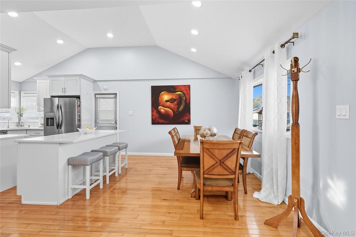 Dining space with light wood finished floors, vaulted ceiling, plenty of natural light, and recessed lighting