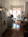 Kitchen featuring refrigerator, range, white cabinetry, dark wood-style flooring, and ornamental molding