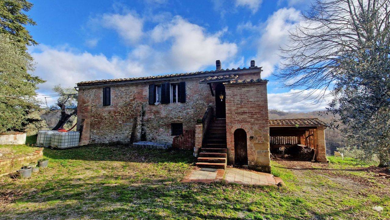 15th-century farmhouse with annexes, 1 hectare of land and panoramic views of the Crete Senesi for sale in Asciano, Tuscany.