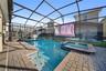 Private screen enclosed pool and hot tub with projector screen, outdoor dining, and lounge area.