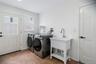 Dedicated laundry space featuring a utility sink and a side entrance door and window for natural light