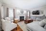 Living room featuring hardwood flooring and a wood burning fireplace with a white mantel and hearth