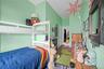 Room featuring a white bunk bed, light green walls, wood-finish flooring, and a white interior door
