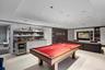 Rec room with a tray ceiling, light colored carpet, wet bar, beverage cooler, and recessed lighting