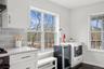 Kitchen featuring wine cooler, stainless steel microwave, backsplash, and white cabinets