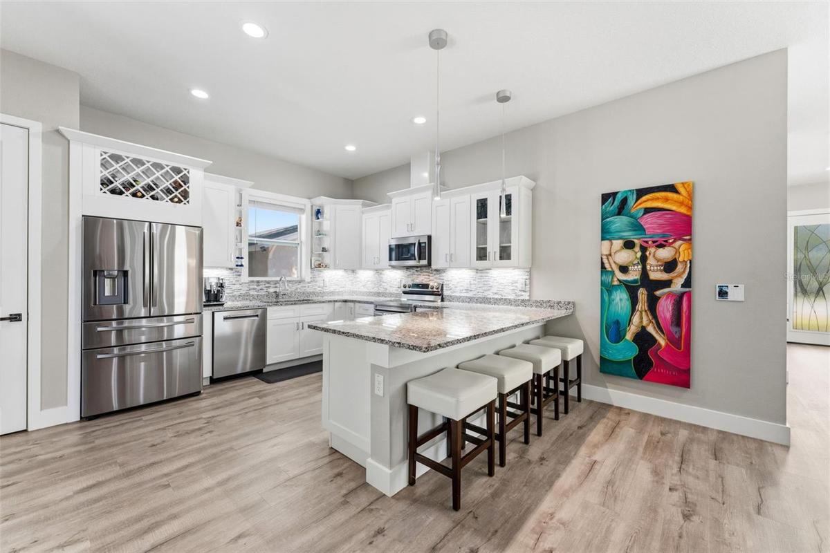 Open-concept kitchen with solid-wood cabinetry, granite countertops, stainless steel appliances, and custom lighting including under-counter kitchen l
