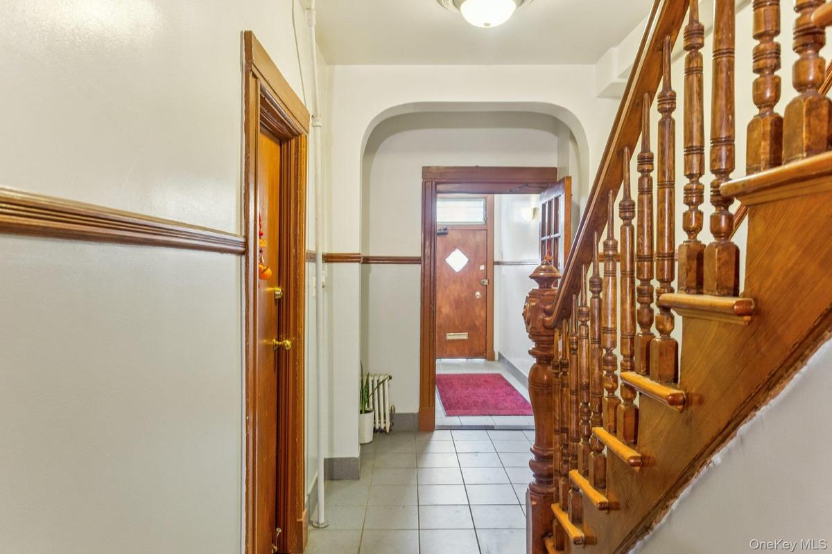 Hallway featuring arched walkways, tile patterned flooring, and stairs