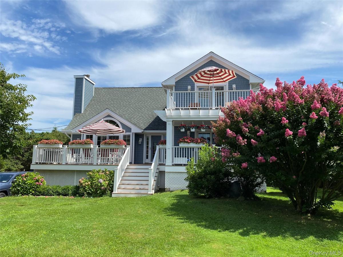 View of front of property with a shingled roof, a front lawn, a chimney, stairway, and covered porch