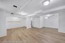 Spacious lower level featuring light wood-finish flooring, recessed lighting, white painted walls, and a built-in shelving unit
