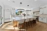 Kitchen featuring glass insert cabinets, a kitchen island, light wood finished floors, a kitchen bar, and recessed lighting