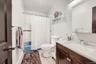 Bathroom featuring a vanity with a white countertop and wood-finish cabinetry, a built-in medicine cabinet with integrated lighting, a toilet, and a b