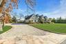 View of front facade featuring a chimney, a front lawn, and gravel driveway