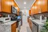 Kitchen featuring light stone counters, brown cabinetry, stainless steel appliances, decorative backsplash, and recessed lighting