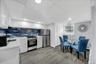 Kitchen and dining area featuring white cabinetry, a blue subway tile backsplash, stainless steel appliances