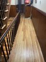 Hallway featuring light wood-style floors, a wainscoted wall, stairway, and wooden walls